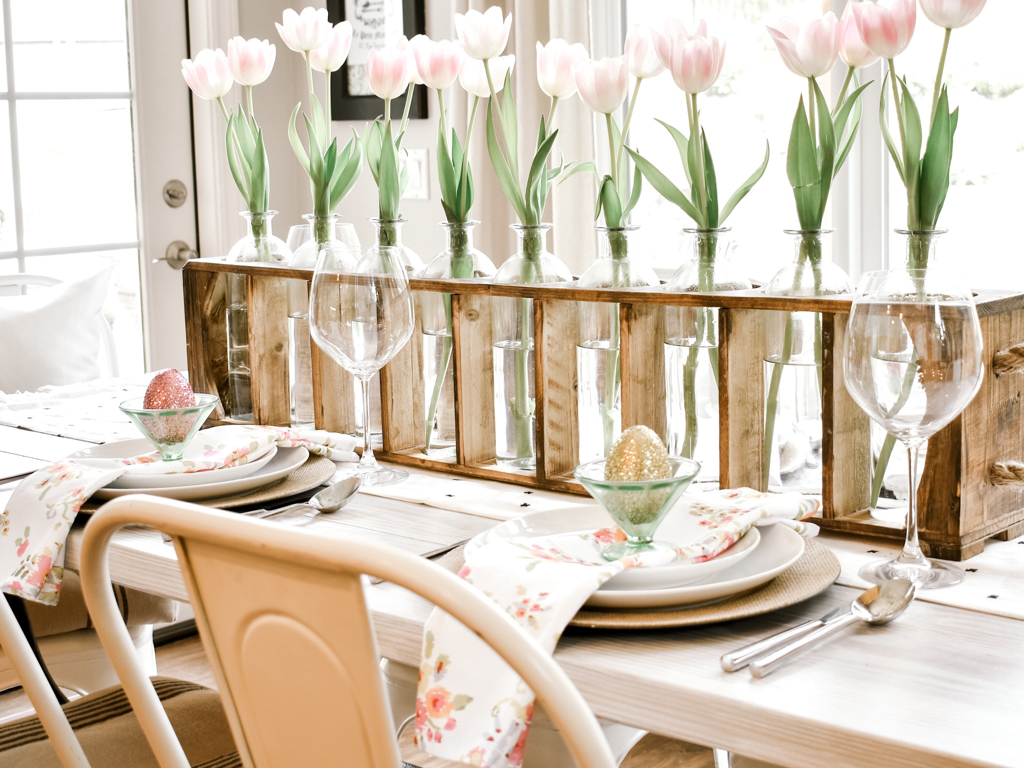 Easter table setting with simple pink tulips, white dinnerware, floral napkins and vintage green depression glass.